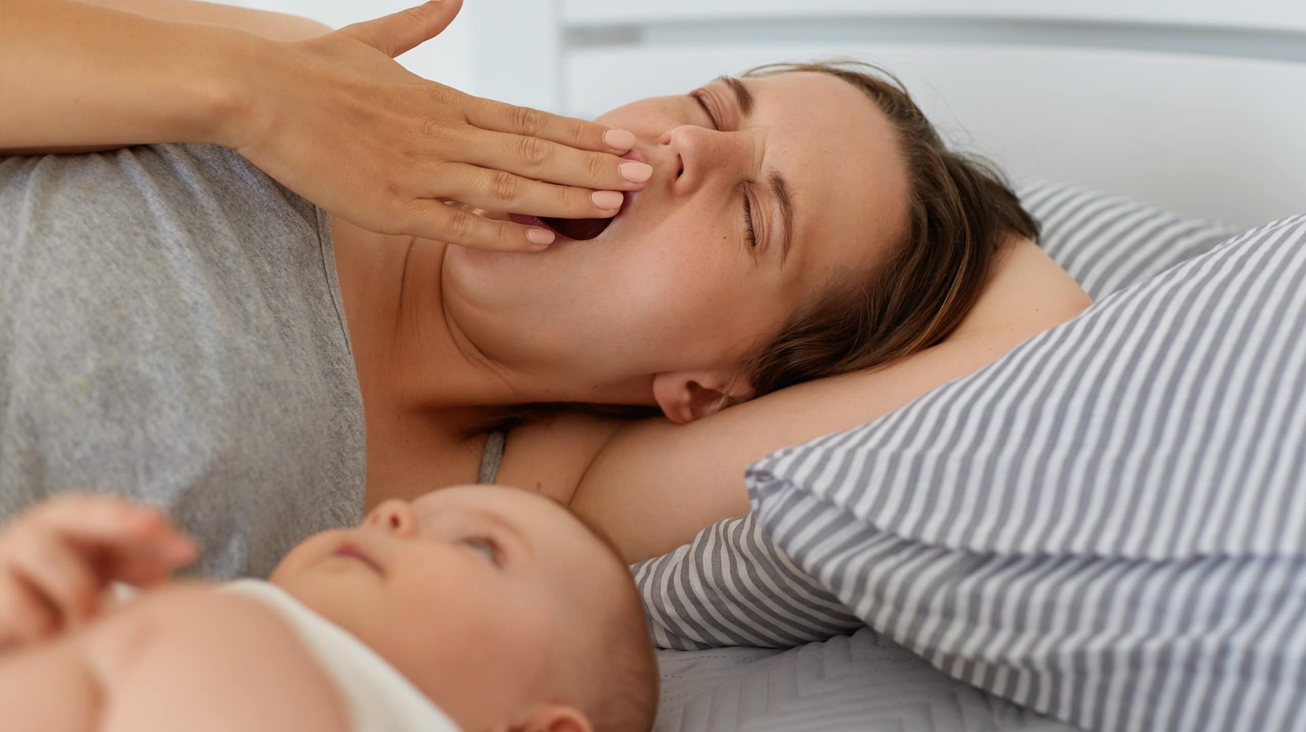 Jeune maman fatiguée tenant son bébé, illustrant l’épuisement parental
